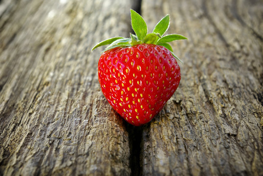 Ripe red strawberry on a wooden background