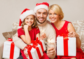 smiling family holding gift boxes and sparkles