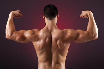 Fototapeta na wymiar Young bodybuilder showing his back muscles on a dark background