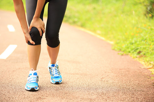 woman runner hold her sports injured knee 