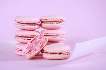 Pink macarons petit fours cookies close up on pink background.