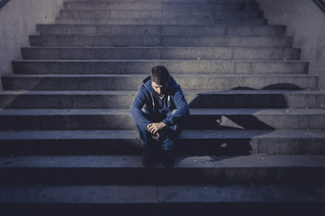 Young man lost in depression sitting on street stairs