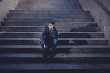 Fototapeta na wymiar Young man lost in depression sitting on street stairs