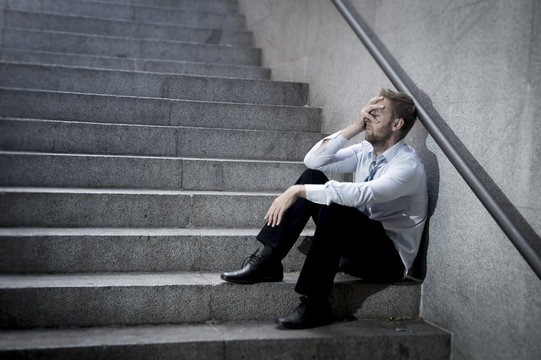 businessman crying in depression sitting on street ground