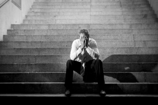 businessman crying in depression sitting on concrete stairs