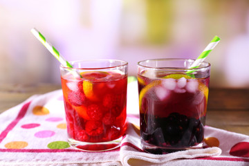 Glasses of cold berry cocktail with lemon on wooden table
