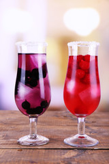 Glasses of cold berry cocktail on wooden table