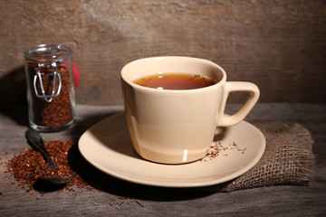 Cup of tasty rooibos tea, on wooden table