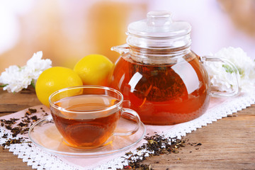 Teapot and cup of tea on table on light background