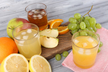 glasses of juice with fresh fruits on grey wooden table