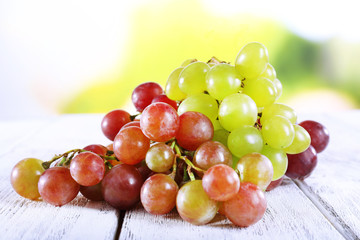 Bunches of ripe grapes on wooden table on natural background