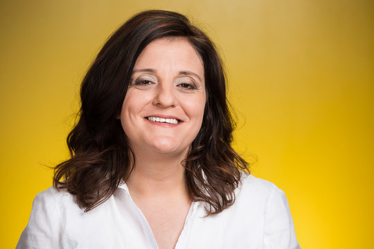 Headshot smiling middle aged woman on yellow background 