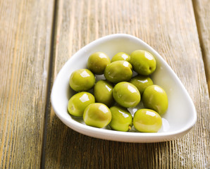 Green olives in bowl on table close-up