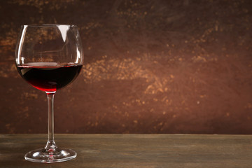 Goblet of red wine on wooden table on wooden wall background