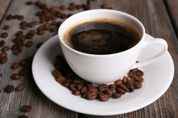 Cup of coffee and coffee beans on wooden background