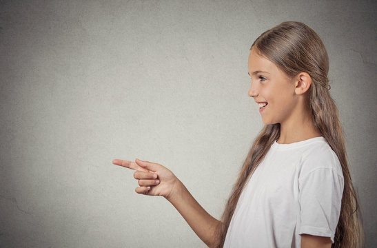 Teenager girl pointing finger at someone, surprised by something