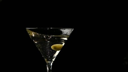 One olive falls into martini glass. Slow motion - Powered by Adobe
