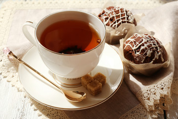 Cup of tea with cupcakes on table, close up
