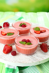 Delicious berry mousse in bowls on table on bright background