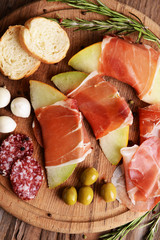 Delicious melon with prosciutto on table close-up