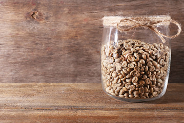 Glass jar of coffee beans  on wooden table on wooden background