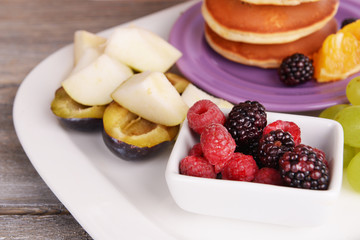 Pancake with fruits and berries on plate on wooden table