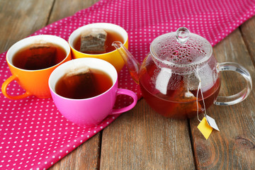 Cups of tea, teapot and tea bags on wooden table close-up