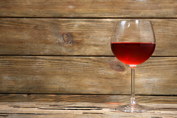 Glass of red wine on wooden table on wooden wall background