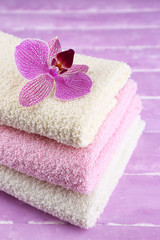 Obraz na płótnie Canvas Orchid flower and towels on color wooden background