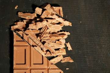 Milk chocolate bar on color wooden background