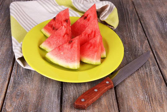 Slices of watermelon on plate on wooden table