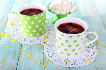 Two polka dot cups of tea and sugar on wooden background