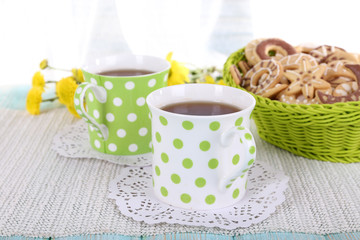 Two polka dot cups of tea with biscuits