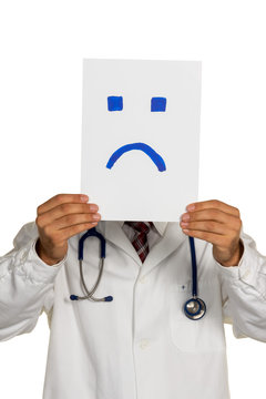 Arzt hält negativen Smiley vor Gesicht