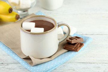 Hot chocolate with marshmallows in mug, on wooden background