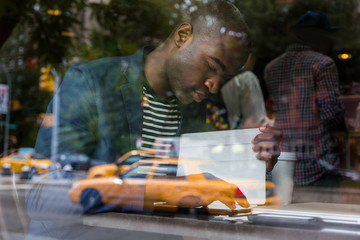 Young Black Man with Digital Tablet in a Cafe - obrazy, fototapety, plakaty