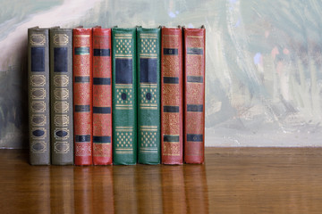 Richly decorated volumes of books with a gold lettering on the b