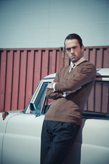 Retro fifties business fashion man leaning against vintage car.