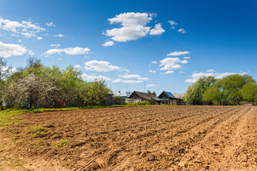 plowed field on a background of rural houses