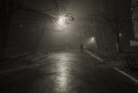 Fototapeta Noir. Silhouette of a passerby on the night street.