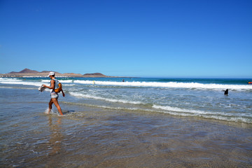 mujer caminando por la playa de famara en lanzarote