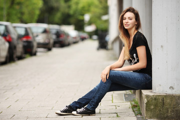 Fototapeta premium Junge Frau sitzt auf Mauer