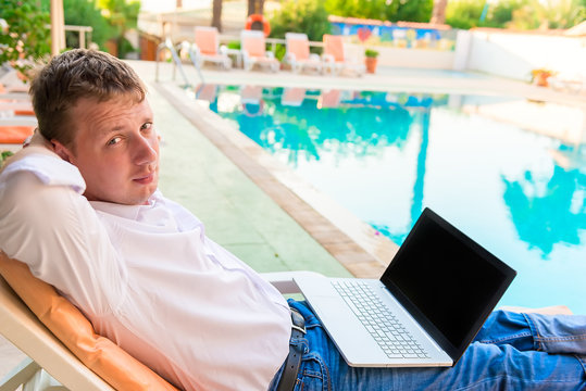 handsome young businessman is resting near the pool