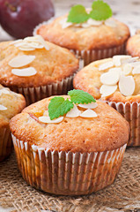 Muffins with plums and almond petals decorated with mint leaves