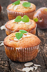 Muffins with plums and almond petals decorated with mint leaves