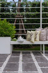 tea set and yellow pillows on white wodden bench