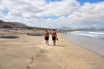 pareja caminando por la playa de famara en lanzarote