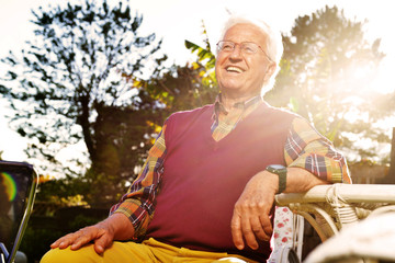 anziano seduto in giardino al tramonto - obrazy, fototapety, plakaty