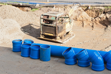 Blaue Kanalrohre am Strassenrand und ein Sandrüttler