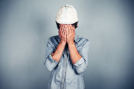 Blue collar worker covering his face